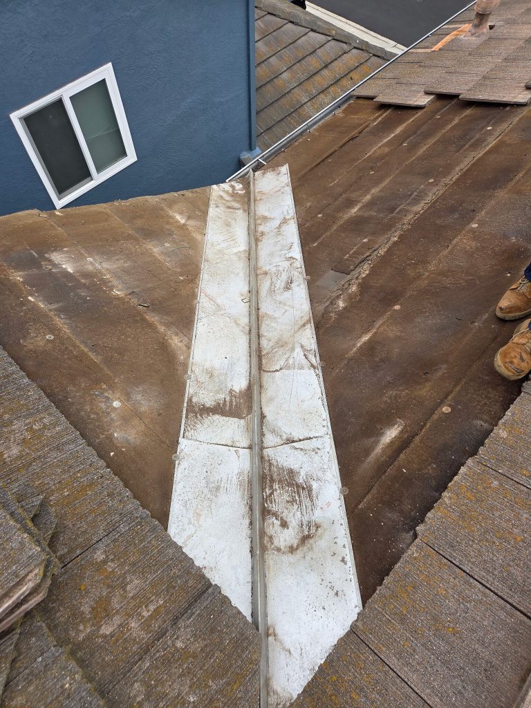 roof section with old tiles removed, exposing underlayment for inspection