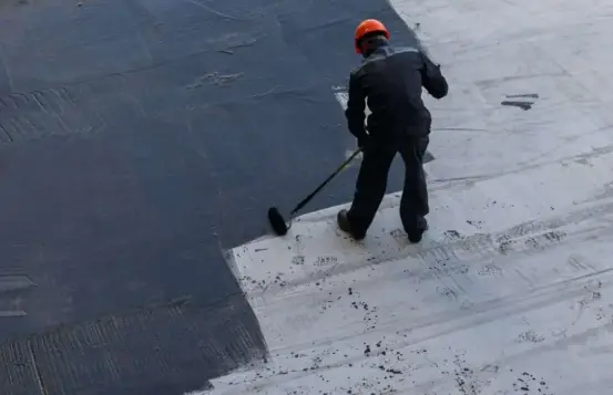 roofer applying liquid primer coating for modified bitumen flat roof waterproofing in san diego