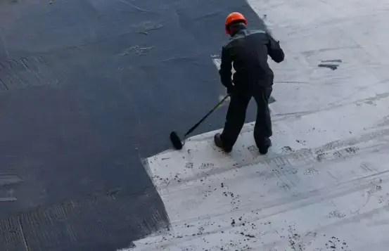 roofer applying liquid primer coating for modified bitumen flat roof waterproofing in san diego